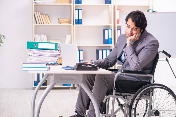 Молодий красивий працівник в інвалідному візку в офісі
 - Фото, зображення