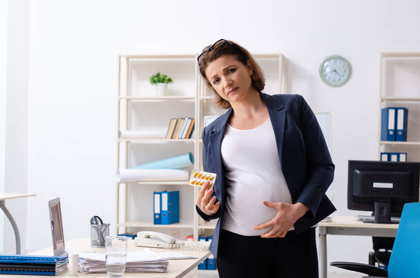 Vieja embarazada trabajando en la oficina - Foto, imagen