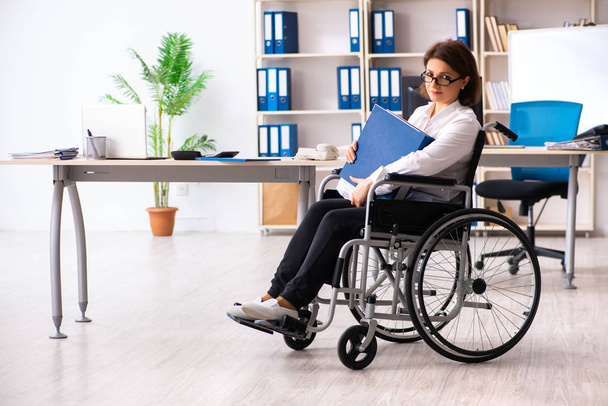 Ofisteki tekerlekli sandalyedeki kadın çalışan. - Fotoğraf, Görsel