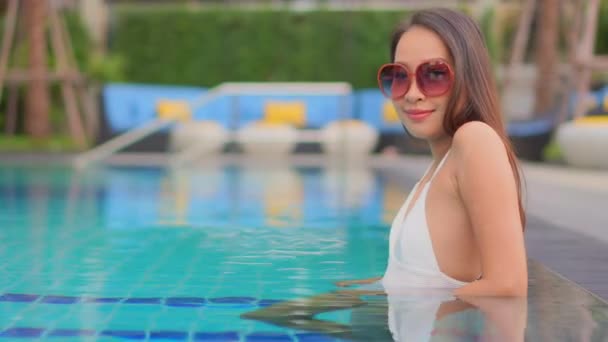 footage of beautiful Asian woman relaxing in pool at hotel - Filmmaterial, Video