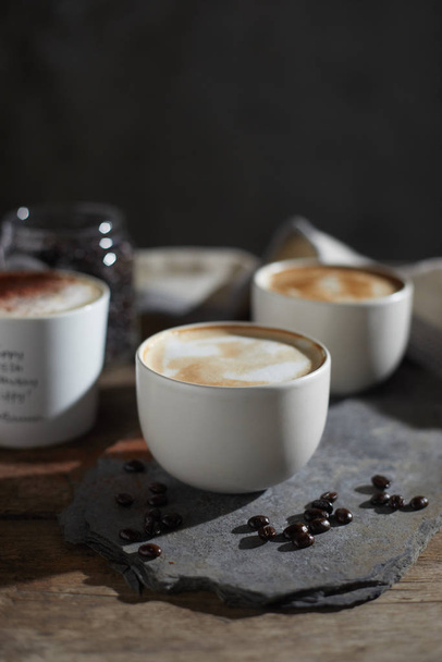 Taza de café caliente y granos de café en mesa de madera
 - Foto, imagen