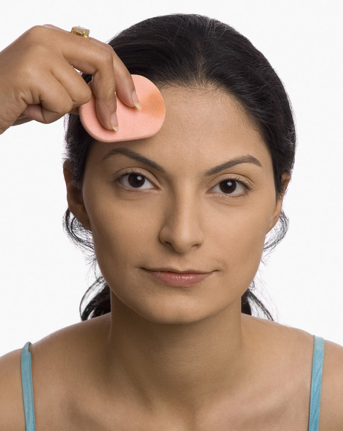 Hand applying powder puff on a young woman's face - Fotó, kép