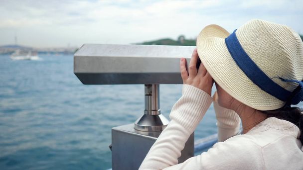 vrouw kijkt door verrekijker verkennen kust op dijk - Foto, afbeelding