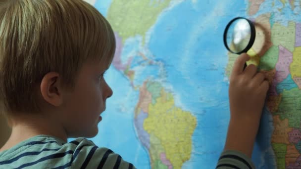 The boy looks at the map through a magnifying glass - Footage, Video