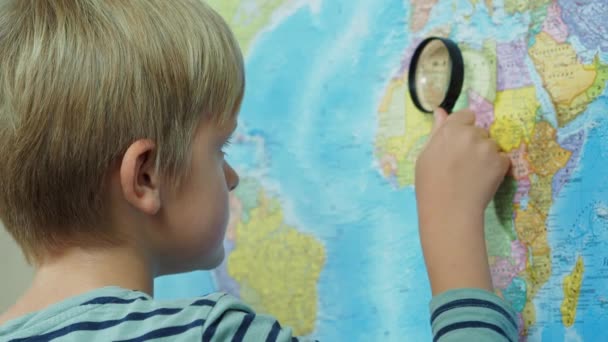 El niño mira el mapa a través de una lupa
 - Imágenes, Vídeo
