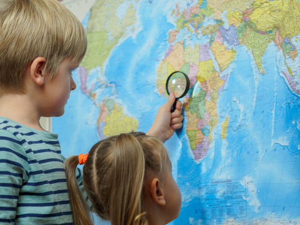 Brother and sister  learning a map through a magnifying glass - 写真・画像