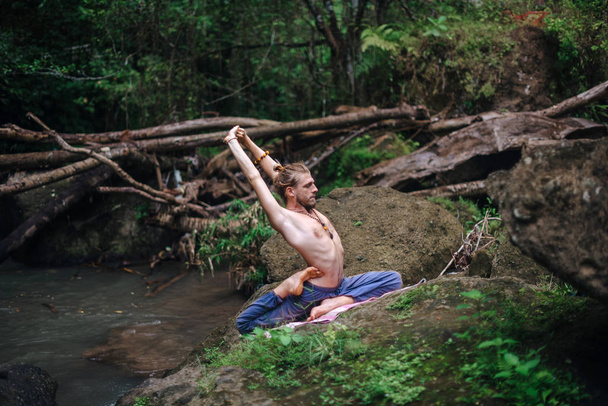 Práctica de yoga y meditación en la naturaleza. Hombre practicando cerca del río
 - Foto, imagen