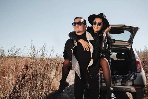 Happy Traveling Couple Dressed in Black Stylish Clothes Enjoying a Car Trip on the Field Road, Vacation Concept - Foto, Imagem