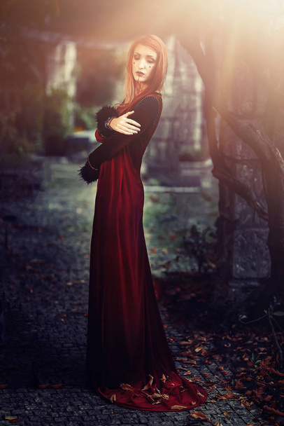Młoda kobieta, czerwony aksamit historyczna sukienka i złoty klejnot. - Zdjęcie, obraz