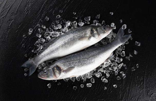 Seabass fish on ice on black stone background, top view - Photo, Image