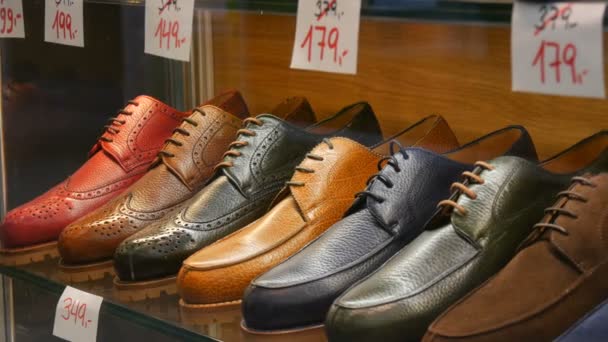 Shelves in the window of shoe store with different classic leather mens shoes in various colors with price tags with discount sales - 映像、動画