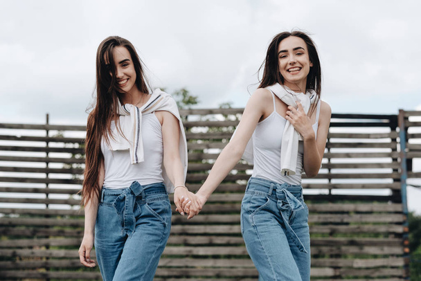 Portret dwóch młodych sióstr Brunetki ubranych jak w dżinsach i białej koszulce, koncepcja Best Friends Forever - Zdjęcie, obraz