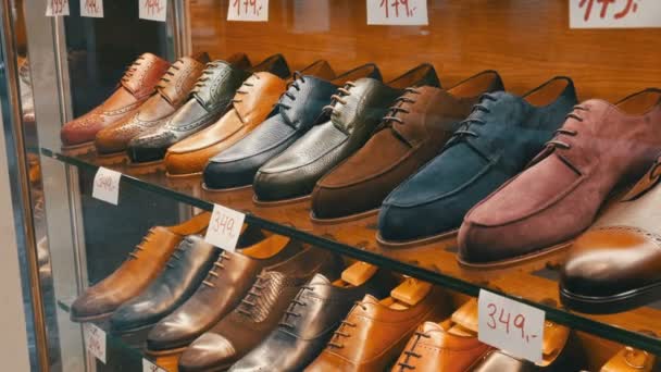 Regale im Schaufenster des Schuhgeschäfts mit verschiedenen klassischen Herrenschuhen aus Leder in verschiedenen Farben mit Preisschildern mit Rabattverkauf - Filmmaterial, Video