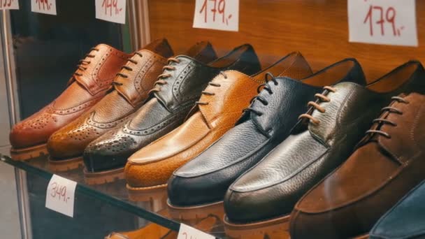 Estantes en la ventana de la tienda de zapatos con diferentes zapatos clásicos de cuero para hombre en varios colores con etiquetas de precios con ventas de descuento
 - Imágenes, Vídeo