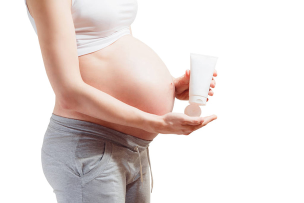 Pregnant young woman with big belly  squeezes a useful cream fro - Foto, immagini