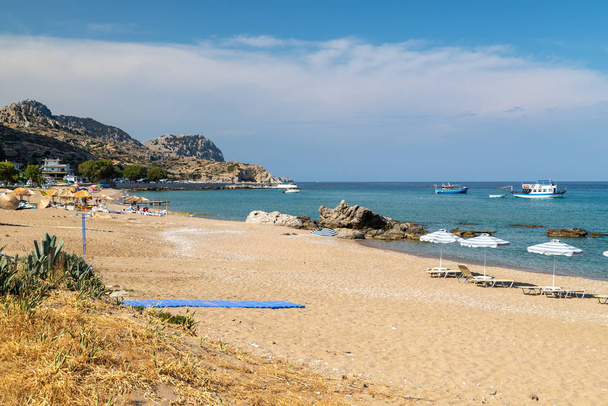 Spiaggia di Stegna sull'isola greca di Rodi con sabbia, ombrelloni e boa
 - Foto, immagini