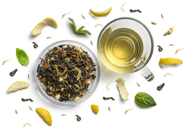 Зеленый чай с натуральными ароматическими добавками и чашкой. Вид сверху на белый фон
 - Фото, изображение