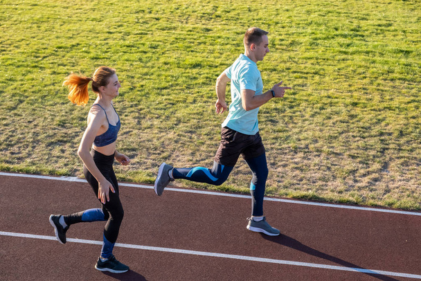 Young couple of fit sportsmen boy and girl running while doing e - Photo, Image