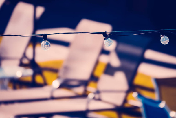 Lampadine a corde davanti alle poltrone a bordo piscina in un motel in t
 - Foto, immagini