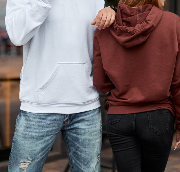 young couple wearing hoodie. man has white hoodie. girl has brown hoodie - Foto, imagen