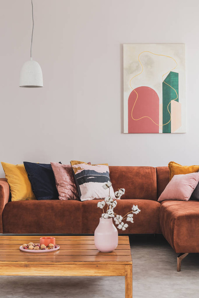 Real photo of a modern painting hanging above a brown, suede corner couch in elegant living room interior - Fotoğraf, Görsel