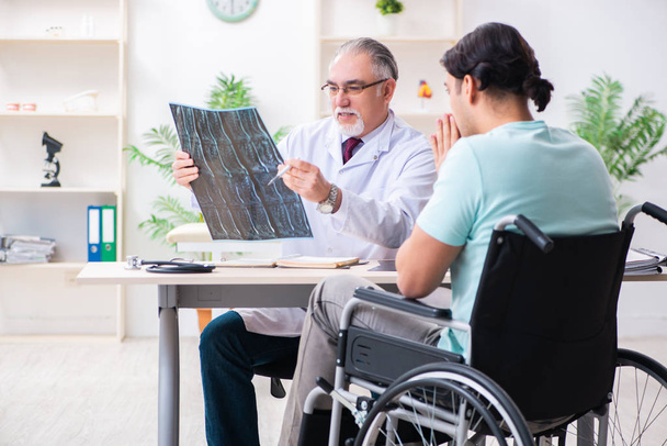 Paciente masculino en silla de ruedas visitando a un viejo médico - Foto, Imagen
