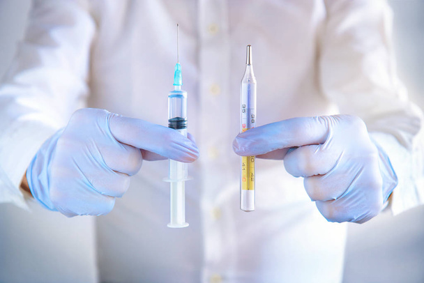 Arzt zeigt medizinisches Werkzeug, Hände halten Spritze und Thermometer  - Foto, Bild