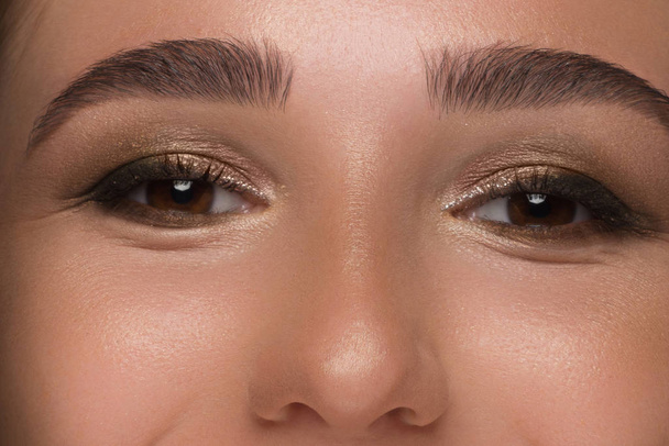 Close-up of woman's eyes with evening make-up. Fashionable shades of eye shadow, extremely long eyelashes and thick smooth eyebrows. Open beautiful look. Clean skin and freckles on face - Φωτογραφία, εικόνα