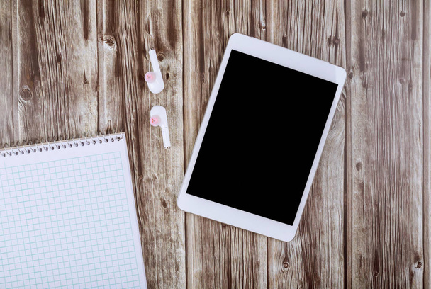 Blank white notebook, wireless headphones and digital tablet on the desk - 写真・画像