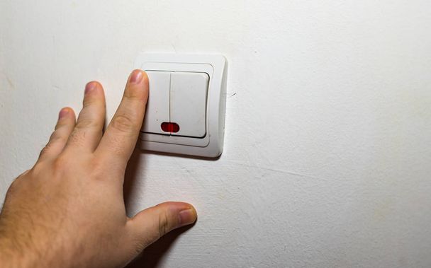 Рука вмикає або вимикає світло на стіні. Перемикач світла крупним планом
 - Фото, зображення