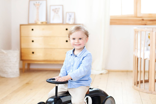 portrait smiling  child riding toy vintage car. Funny kid playing at home. Summer vacation and travel concept. little boy driving a car in the nursery. Toddler driving a retro car, boy in toy car - Fotografie, Obrázek