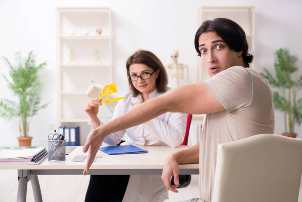 Женщина-врач проверяет гибкость суставов пациентов с помощью гониометра - Фото, изображение