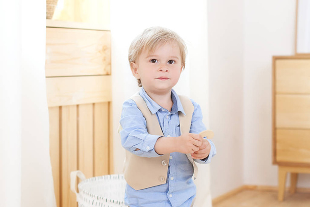 Αγοράκι. Ένα χαρούμενο και χαμογελαστό αγόρι κρατά μια φιγούρα στα χέρια του. Παιδί στο νηπιαγωγείο. Πορτρέτο της μόδας αρσενικό παιδί. Χαμογελαστό αγόρι που ποζάρει. Έννοια του παιδικού στυλ και της μόδας. Σκανδιναβία - Φωτογραφία, εικόνα