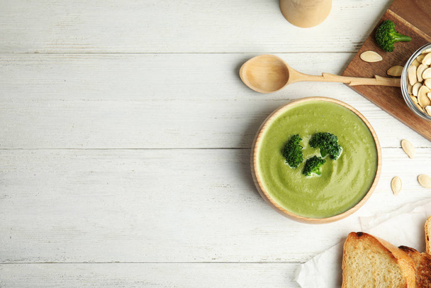 Delicious broccoli cream soup served on white wooden table, flat lay. Space for text - Photo, image