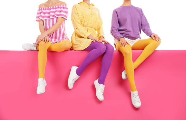 Group of women wearing bright tights and stylish shoes sitting o - 写真・画像