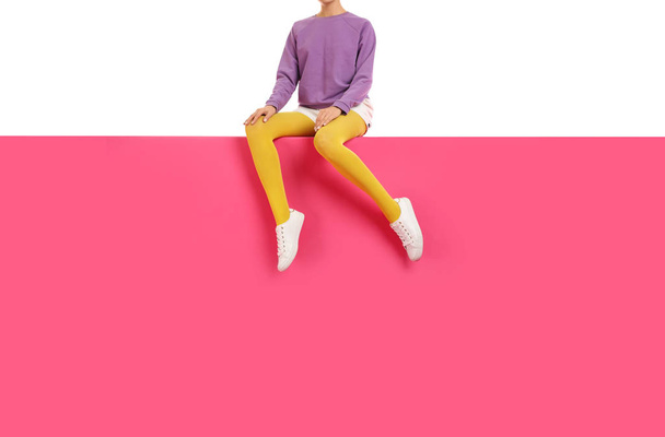 Woman wearing yellow tights and stylish shoes sitting on color b - Foto, afbeelding