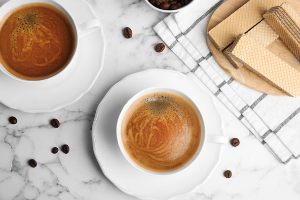 Delicious wafers and coffee for breakfast on white marble table, flat lay - Foto, imagen