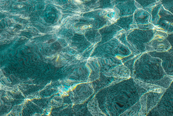 Azure water in the swimming pool. Ripple of water with the reflection of the sun rays. - Photo, Image