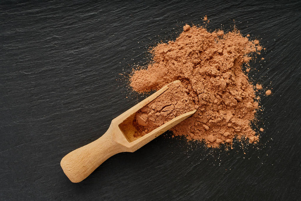 cocoa powder in a wooden scoop  - Foto, afbeelding
