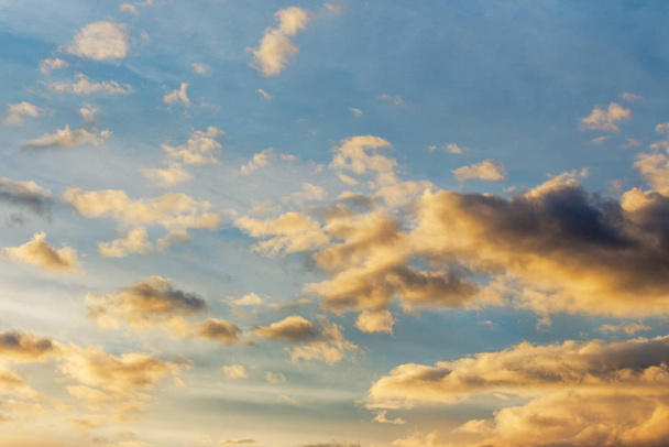 χρυσά σύννεφα σε ένα μπλε ουρανό στο ηλιοβασίλεμα - Φωτογραφία, εικόνα