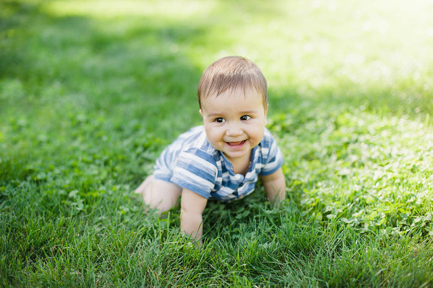 7 month child crawls on grass in yard, - Foto, afbeelding