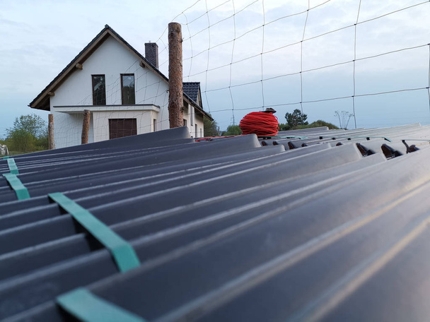 travailleur de la construction sur un toit de rénovation le recouvrant de carreaux à l'aide de marteau, grue et broyeur
 - Photo, image