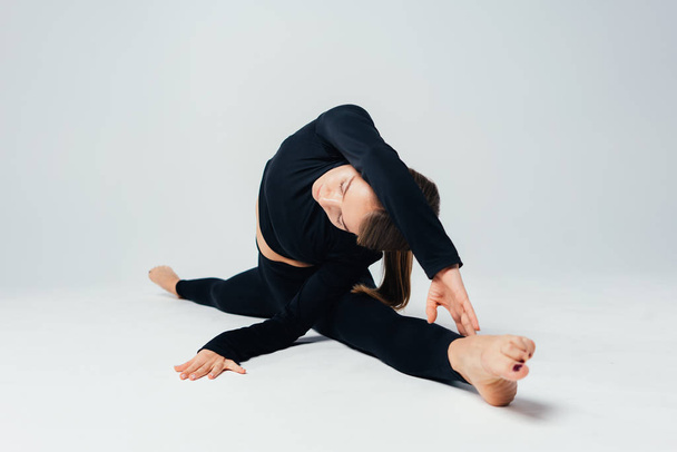 Flexible sporty woman doing yoga exercise against white background. Young fit female athlete doing stretching. Studio shot - Foto, Imagem