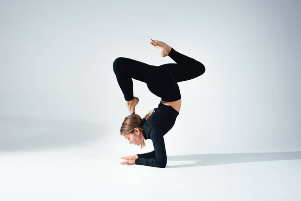 Fitness woman doing stretching exercises in studio. Yoga girl stretches her body - Φωτογραφία, εικόνα