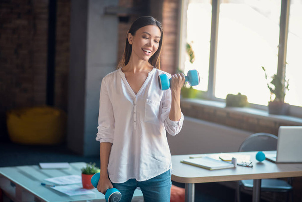 Pretty slim woman having a workout in the office - 写真・画像