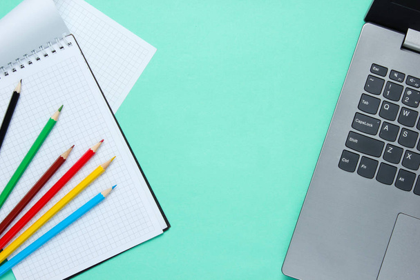 Vissza az iskolai minimalista koncepcióhoz. Laptop, színes ceruzák, notebook kék háttér. - Fotó, kép