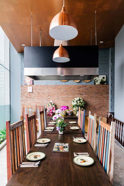Thai modern restoran iç mekanı, masa çatal bıçak, tabak, cam, peçete ve orkidelerle dolu..  - Fotoğraf, Görsel