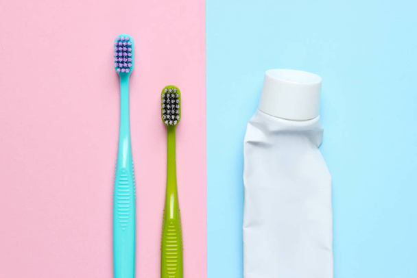 パステルの背景に使用歯磨き粉のチューブを持つ2つの歯ブラシ。トップ表示 - 写真・画像