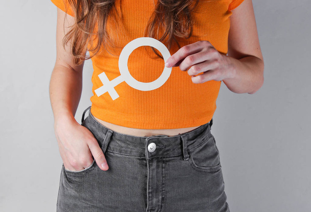 Femen concept. Woman holds in her hands gender feminism symbol on gray background. Crop photo, studio shot - Foto, imagen