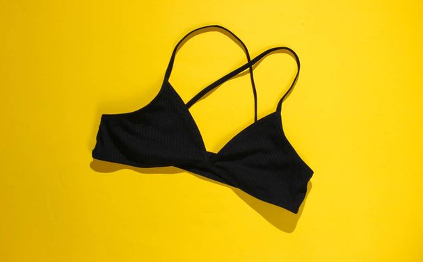 Black fabric bra on a yellow background close-up - Zdjęcie, obraz